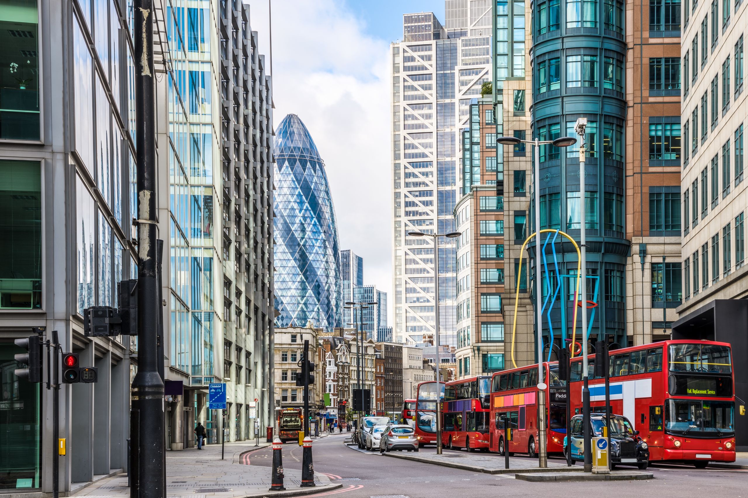 Image of the city of London from he street level. The Gherkin can be seen in the background.