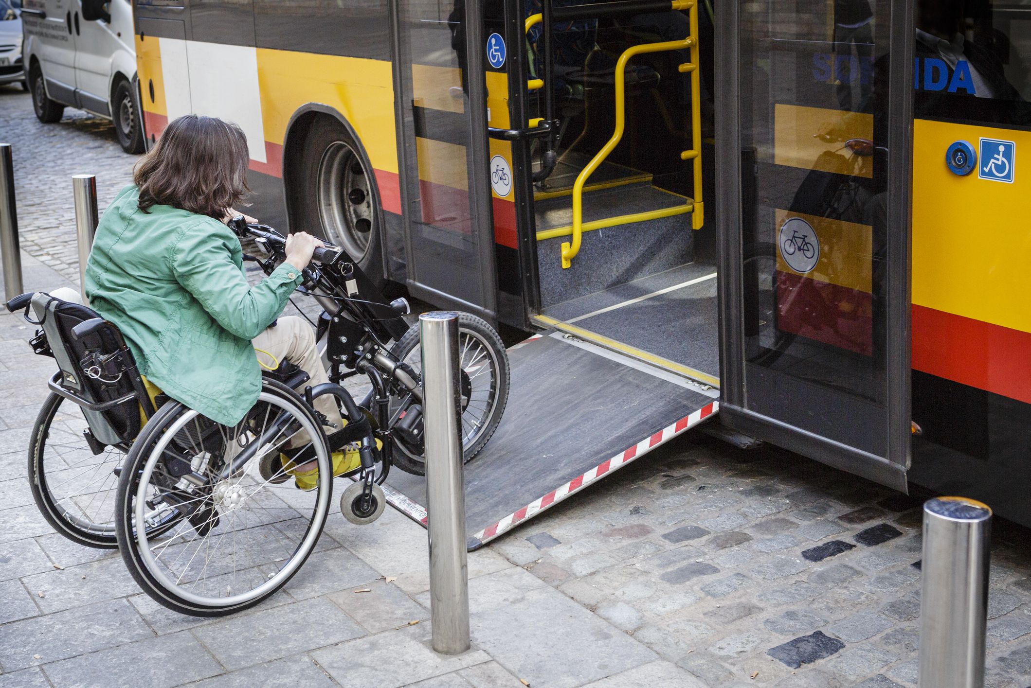 Woman on a mobility scooter boarding a bus via a ramp.