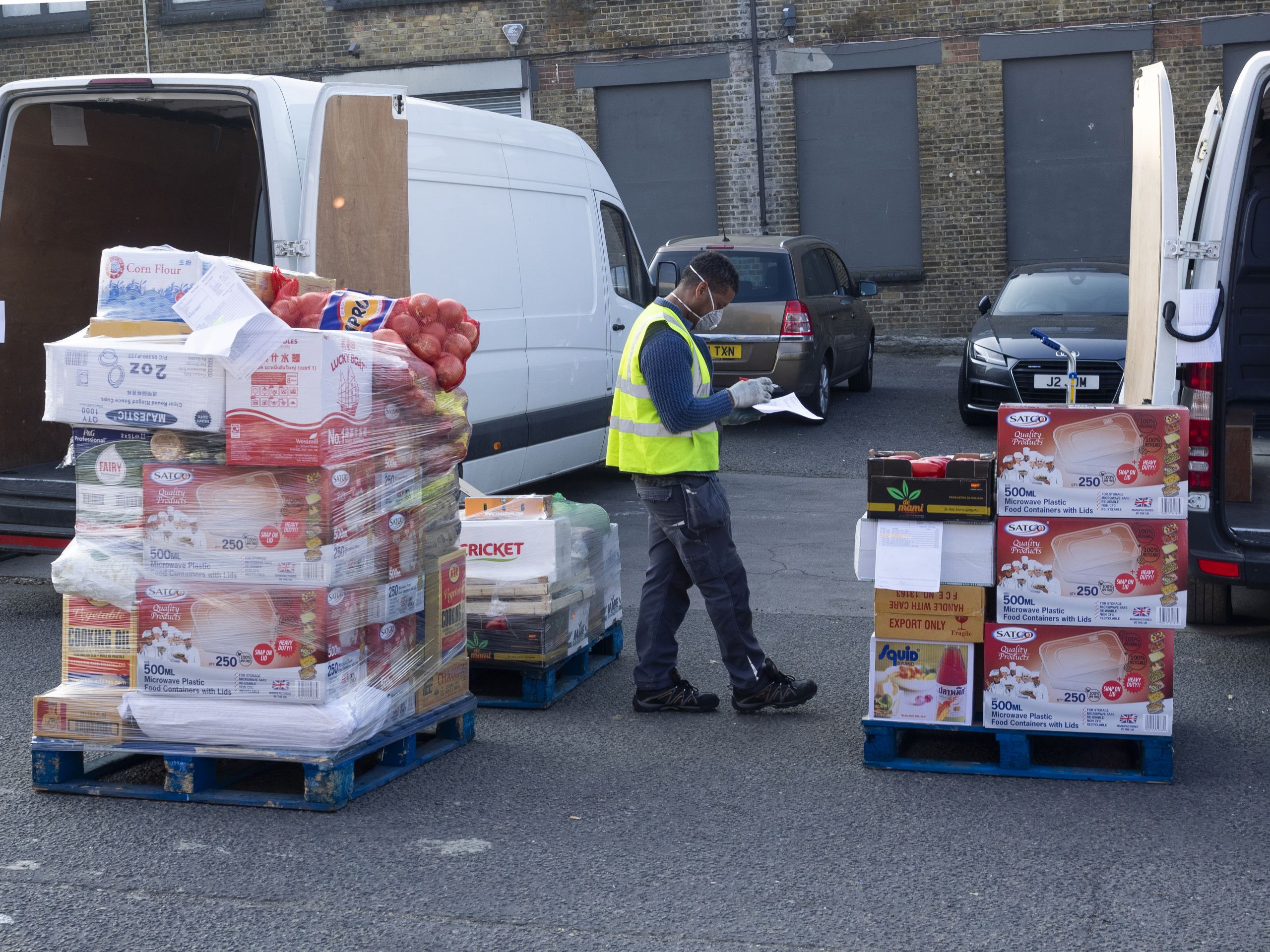 Food delivery driver wearing a mask surrounded by a van and crates of food