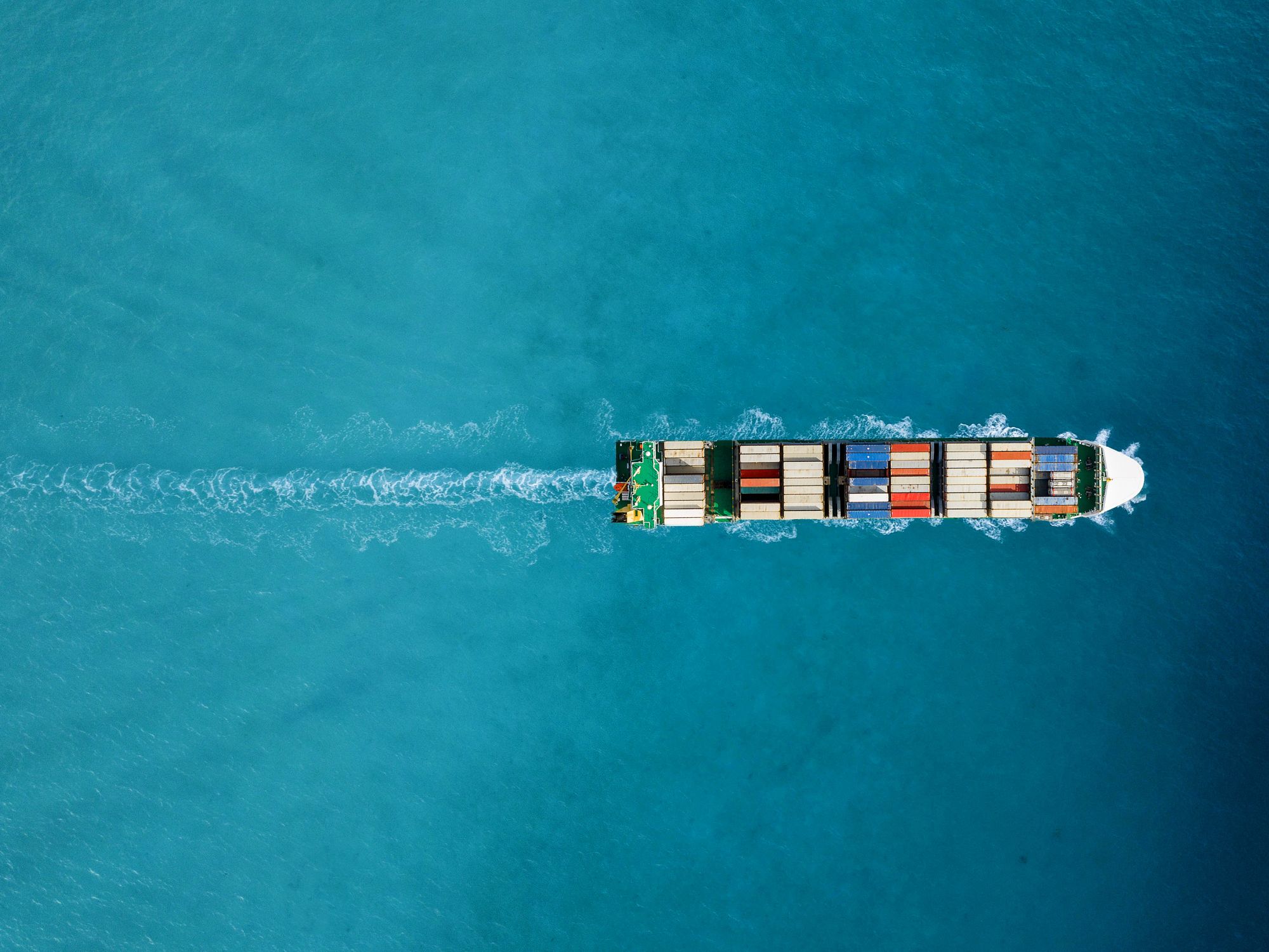 Cargo ship at sea from above full of shipping containers.