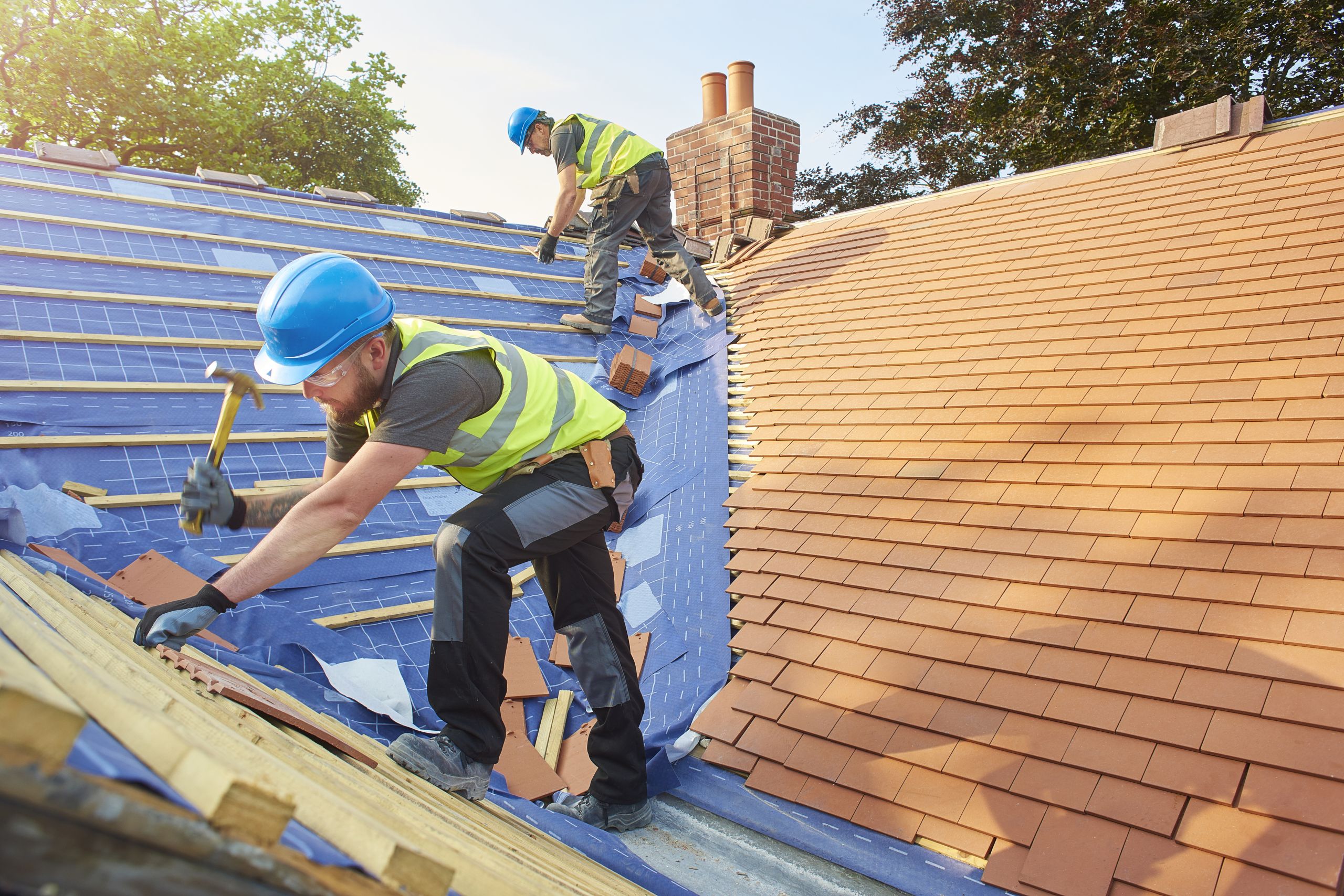 Men on a roof, adding tiling wearing hi viz and hard hats