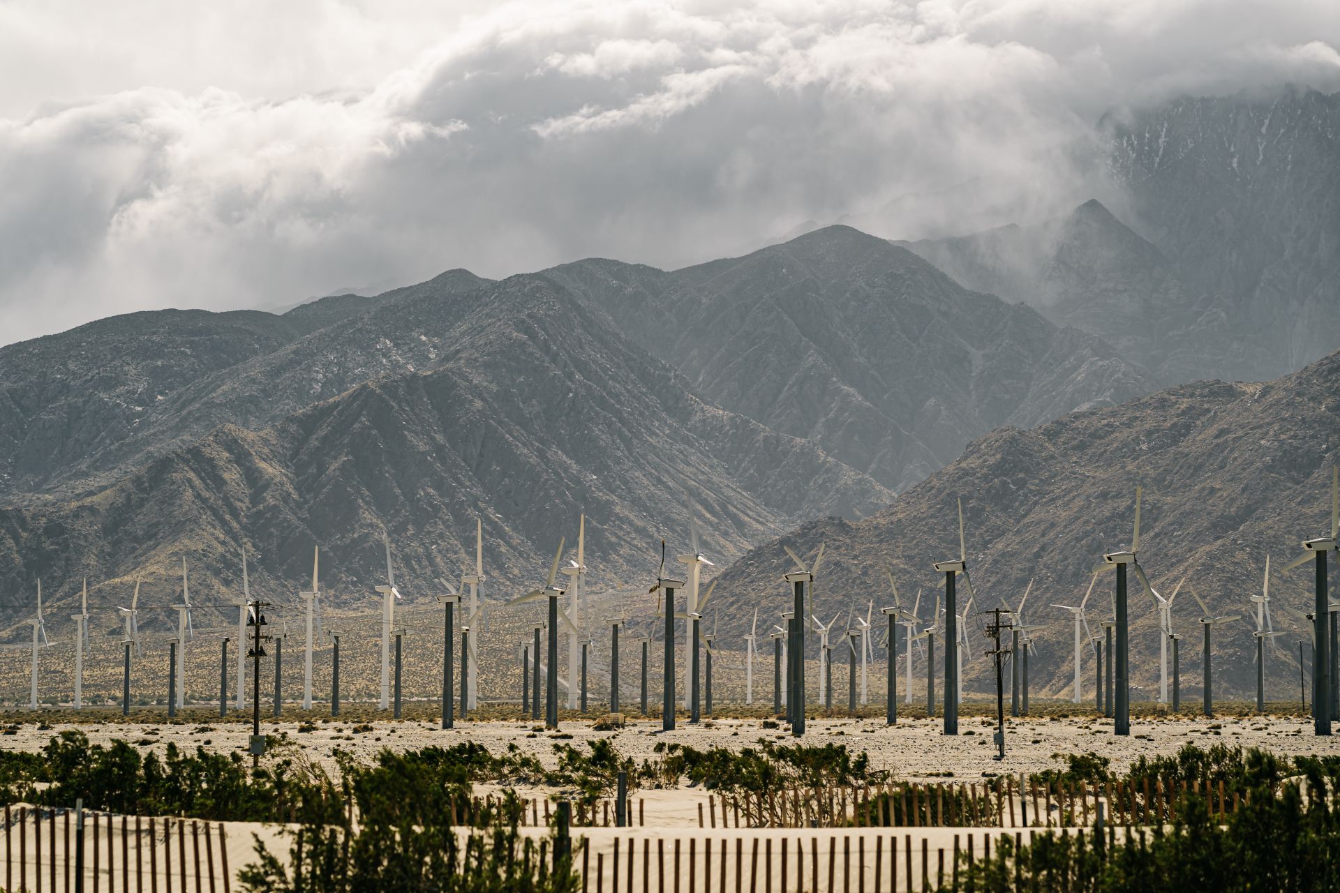 Wind turbines in mountainous valley against cloudy sky