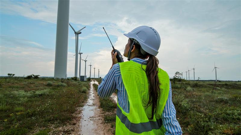photography of woman engineer working on field with windmills