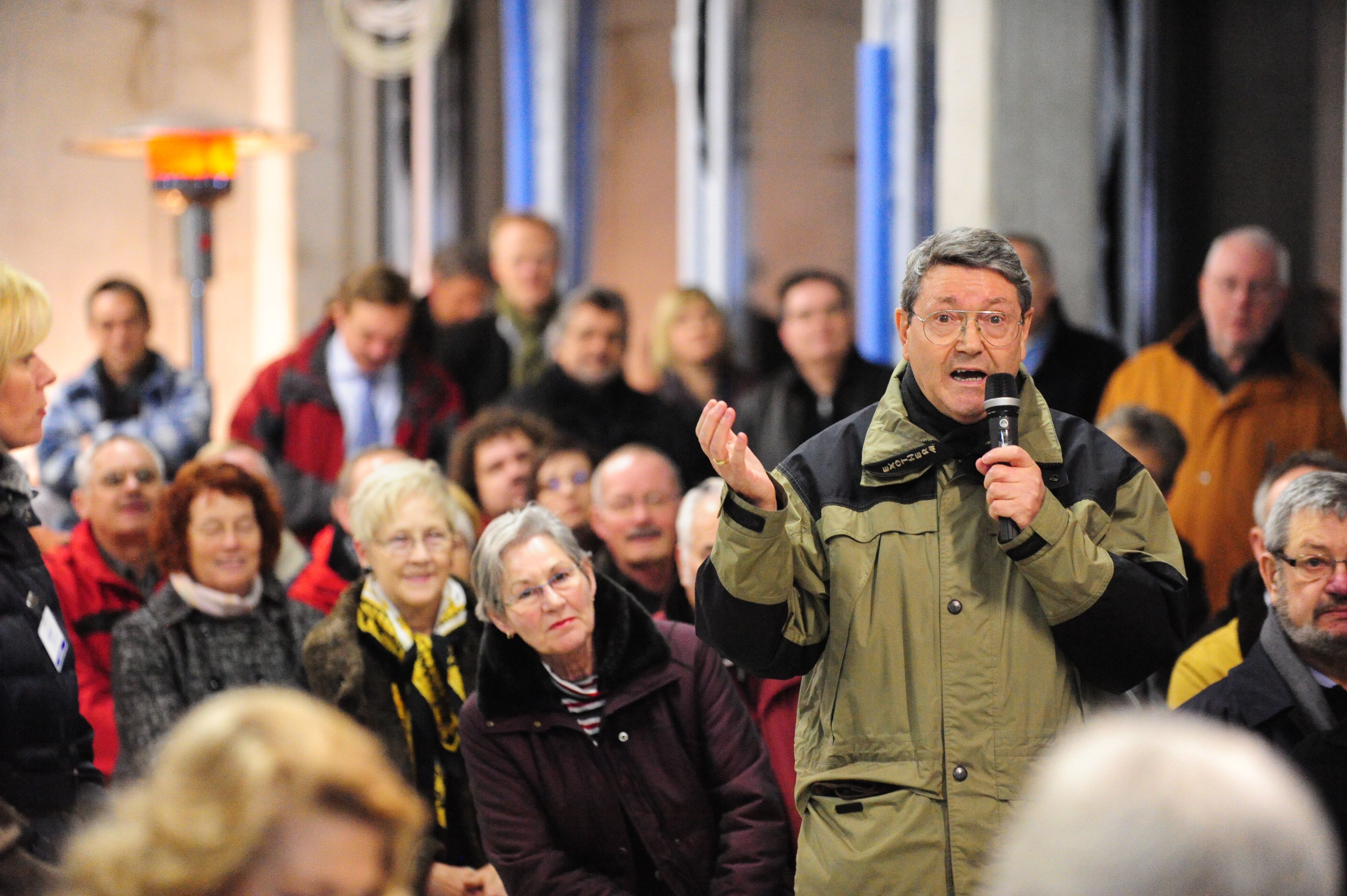 Man talking into a microphone to a large group of people