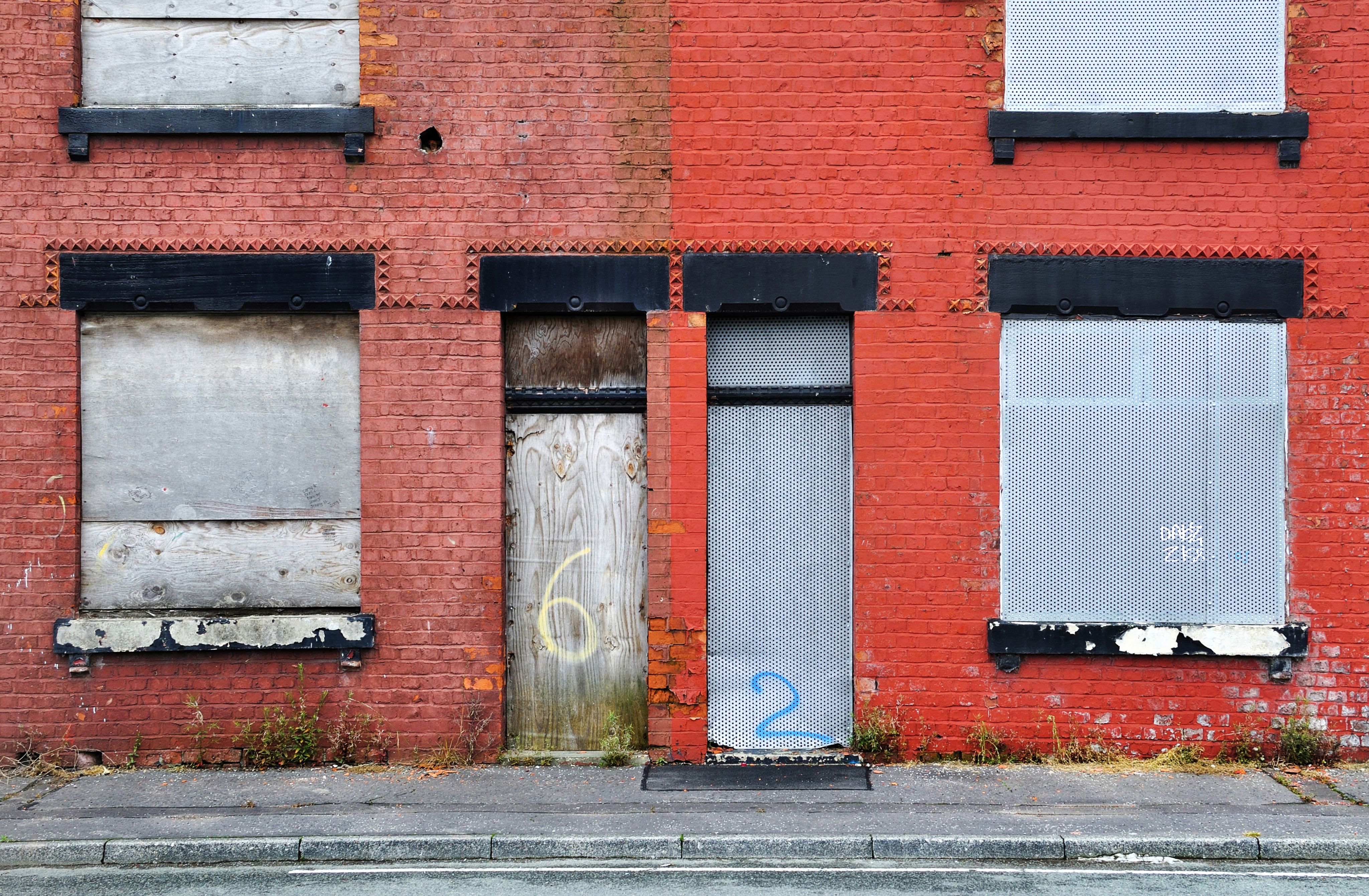 Derelict terraced house in Salford, UK, boarded up and awaiting demolition.