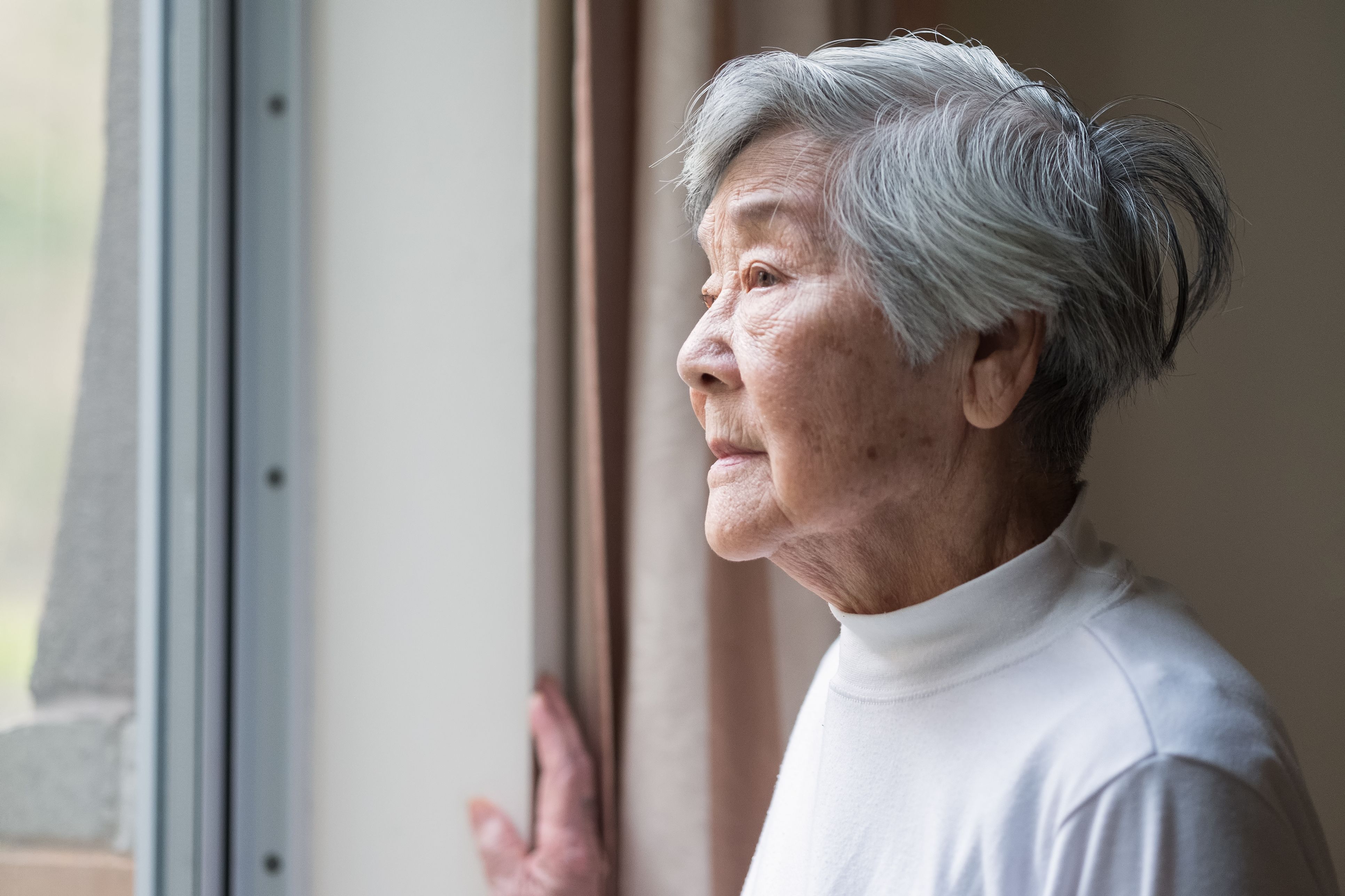An elderly woman looking out of a window