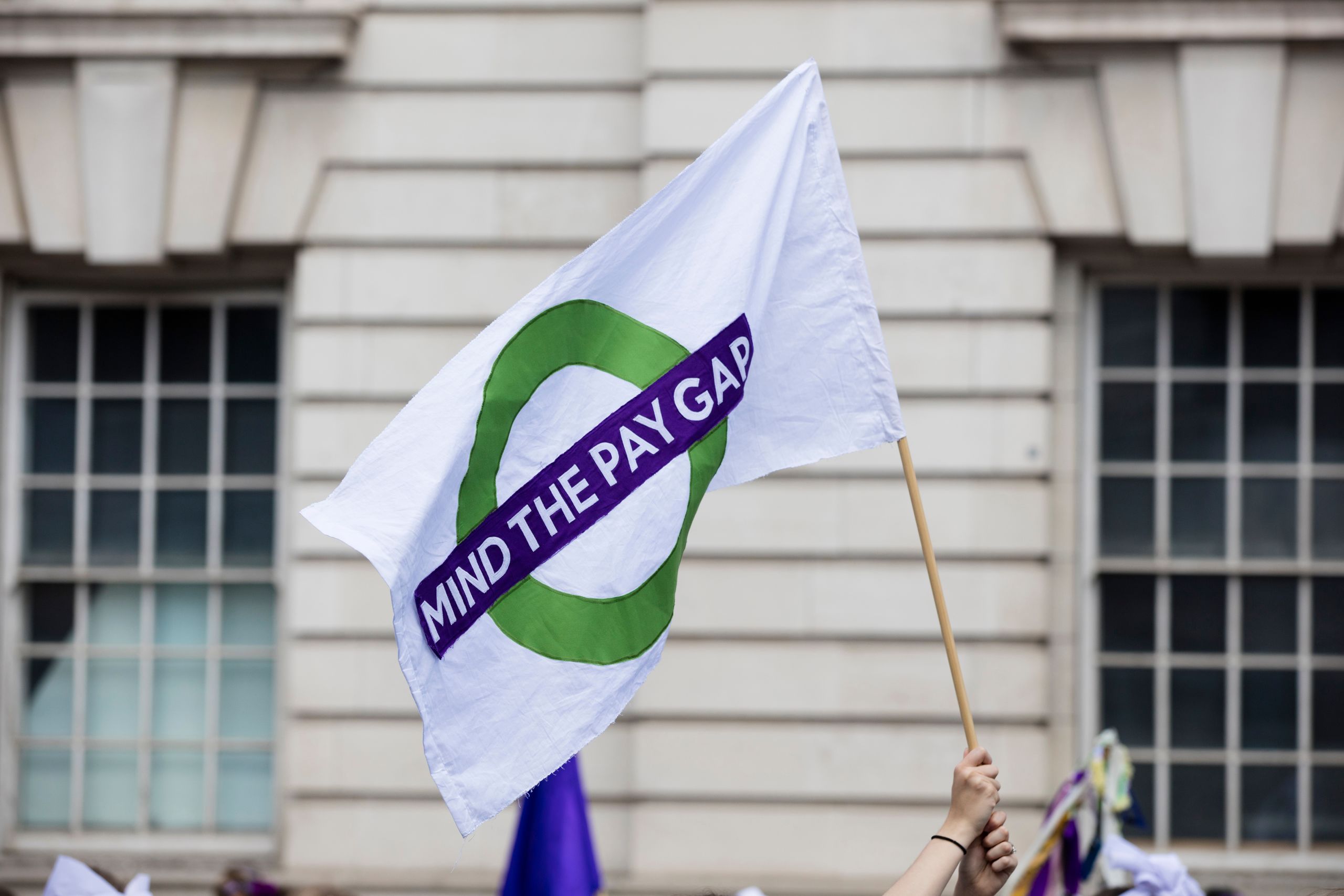 Protesters carrying a 'Mind the pay gap' flag