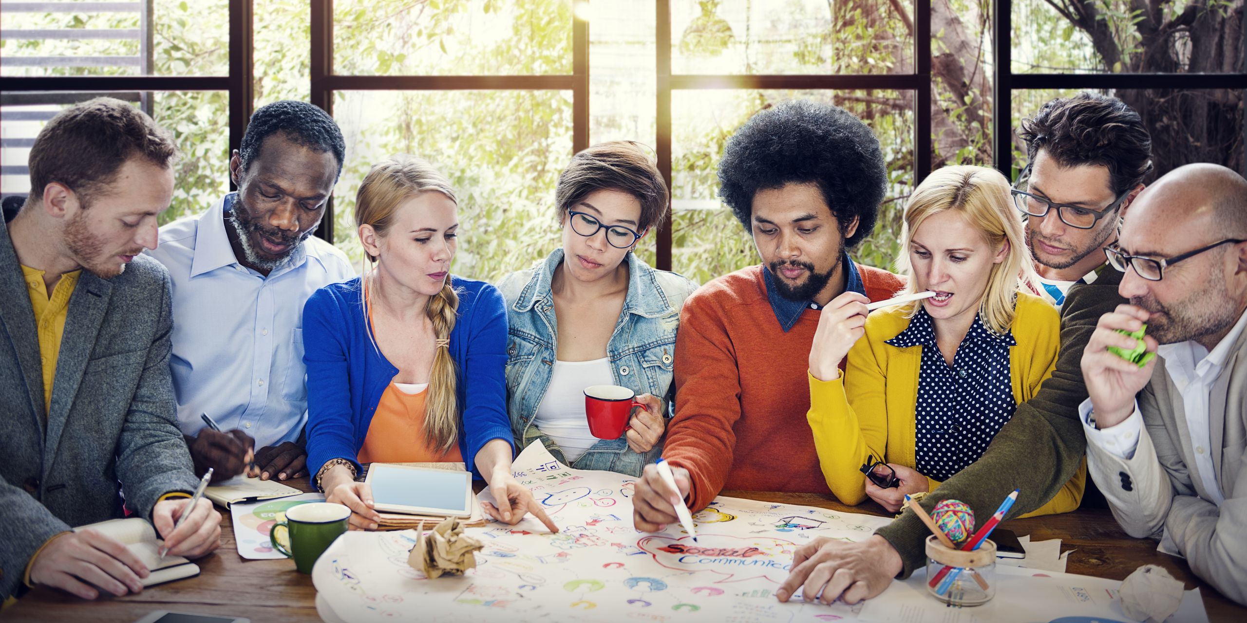Diverse group of people sitting round a table contributing ideas