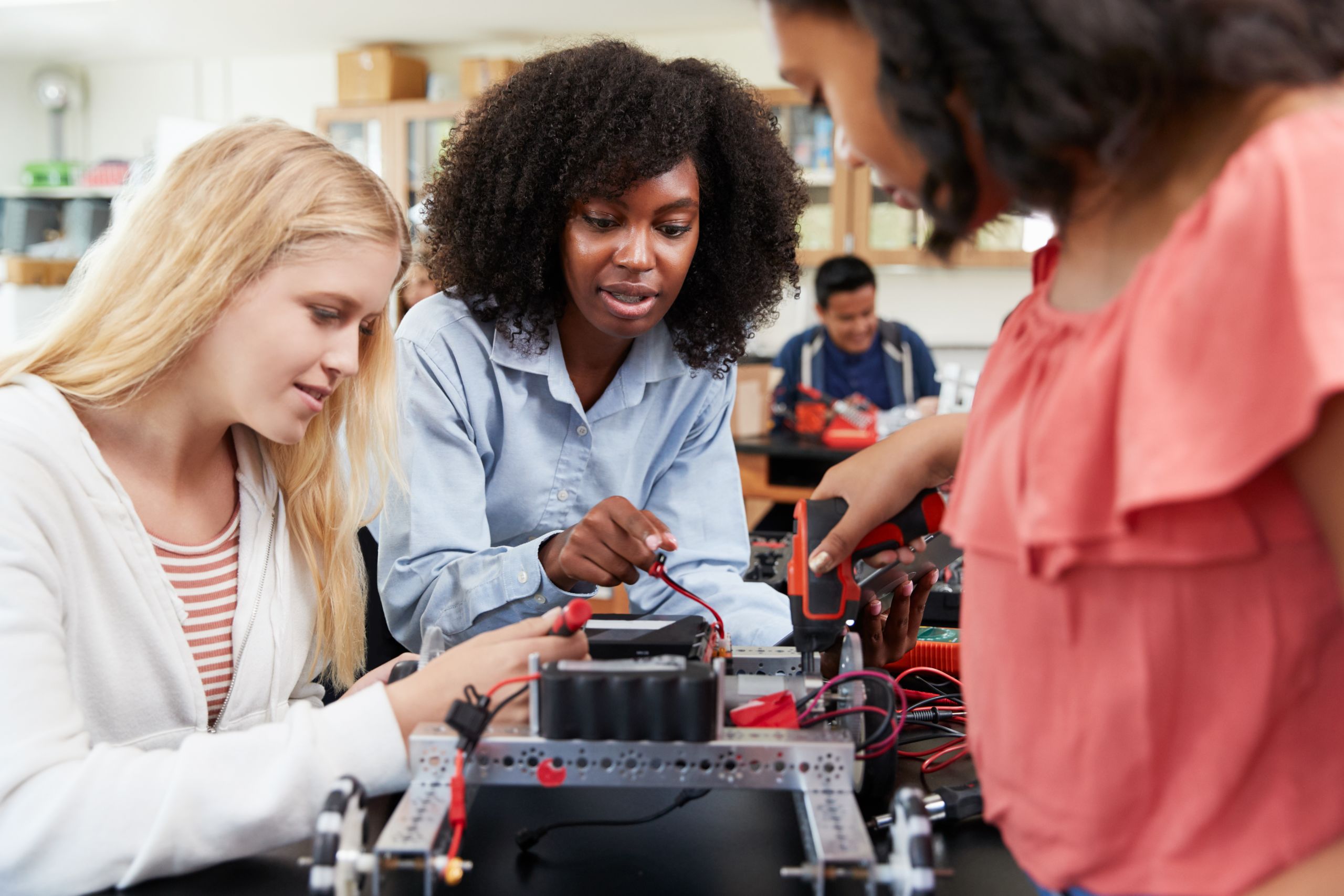 Three young women working on an electrical circuit in a science class