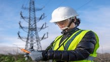 An image of a construction worker with an electricity mast in the background