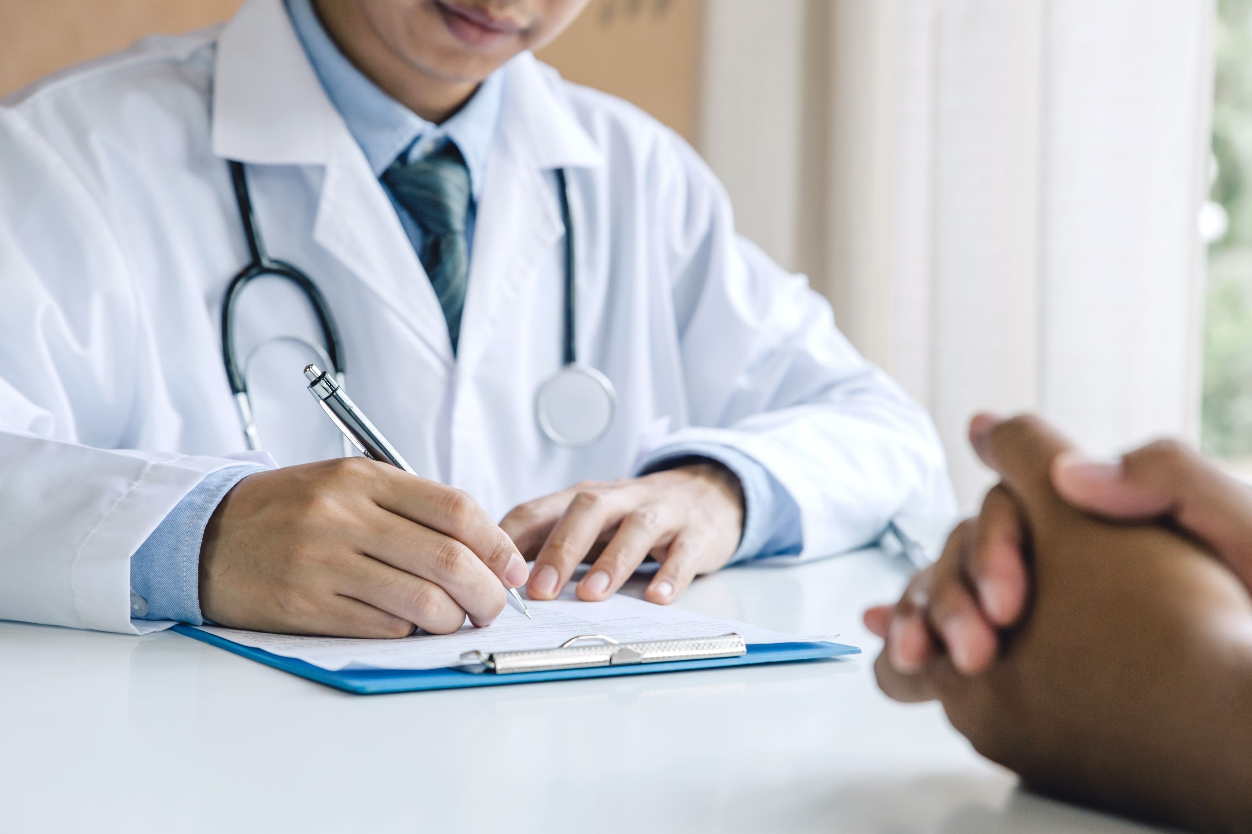 Doctor taking notes in front of a patient