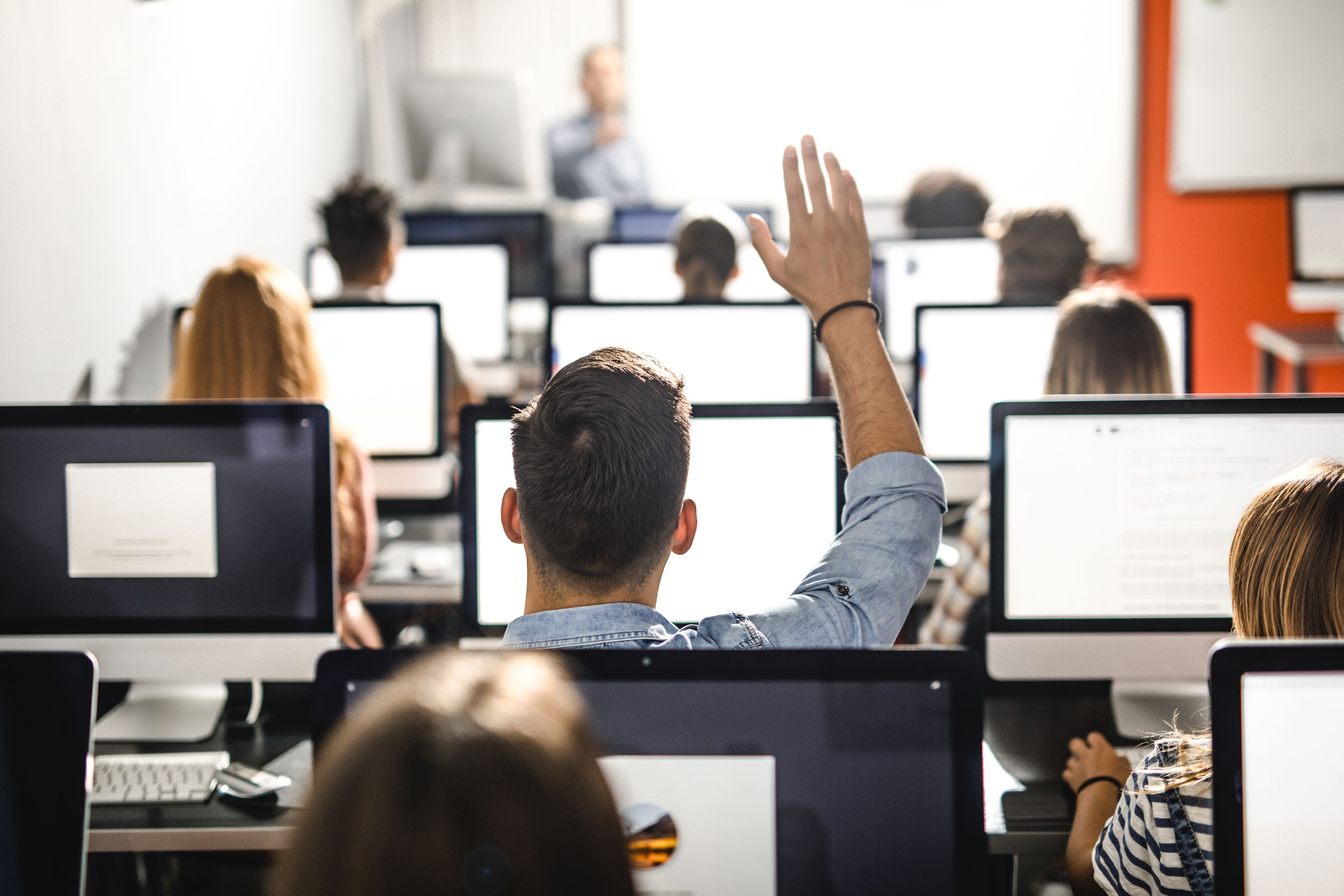 Man working at a computer with his arm raised.