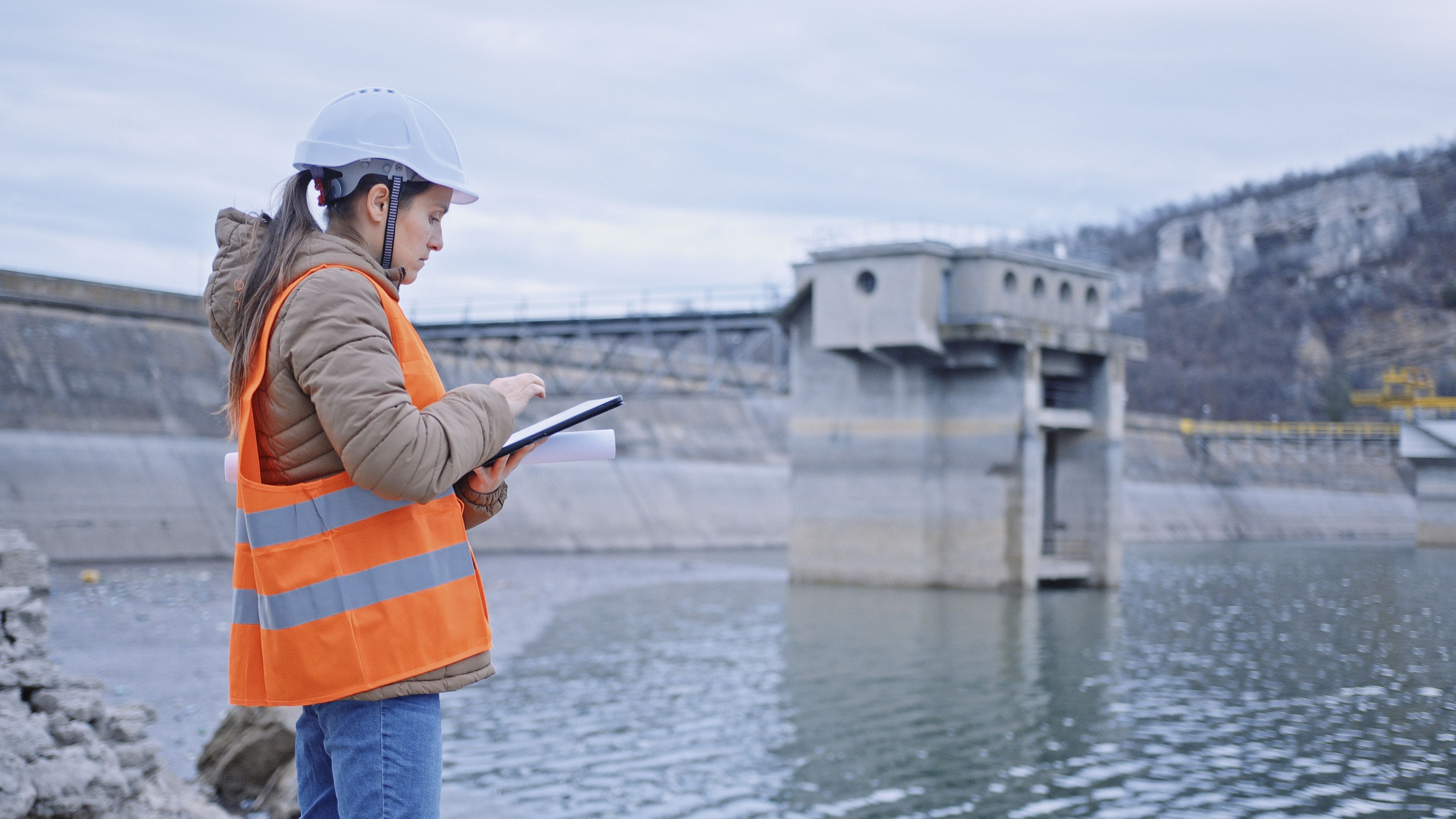 Working day on a water dam with a hydroelectric power plant. Checking the condition of the power equipment, and analysing the data and the results of measurements with a mobile app.