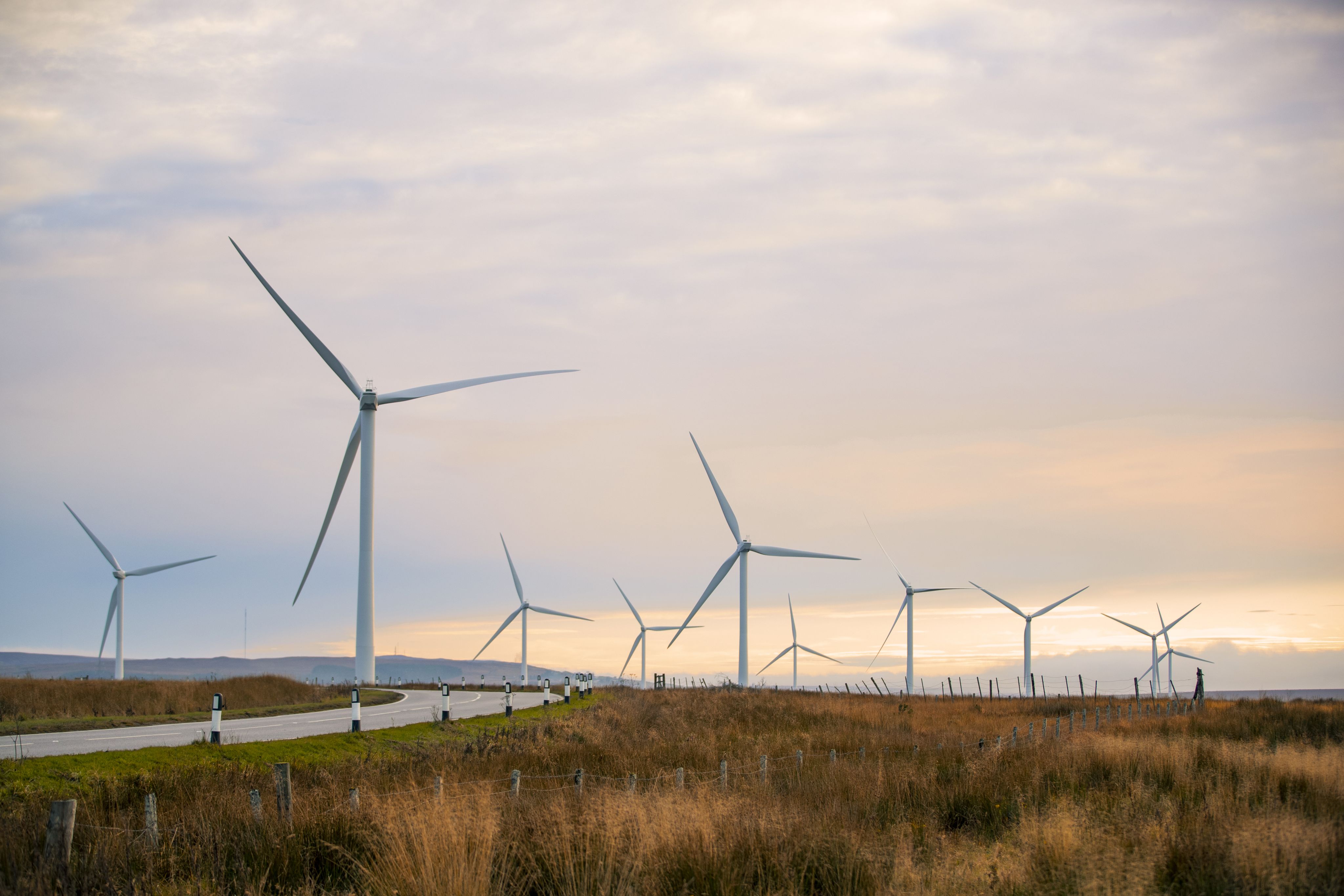 A beautiful sunset in the Scottish highlands with renewable energy wind turbines far into the horizon.