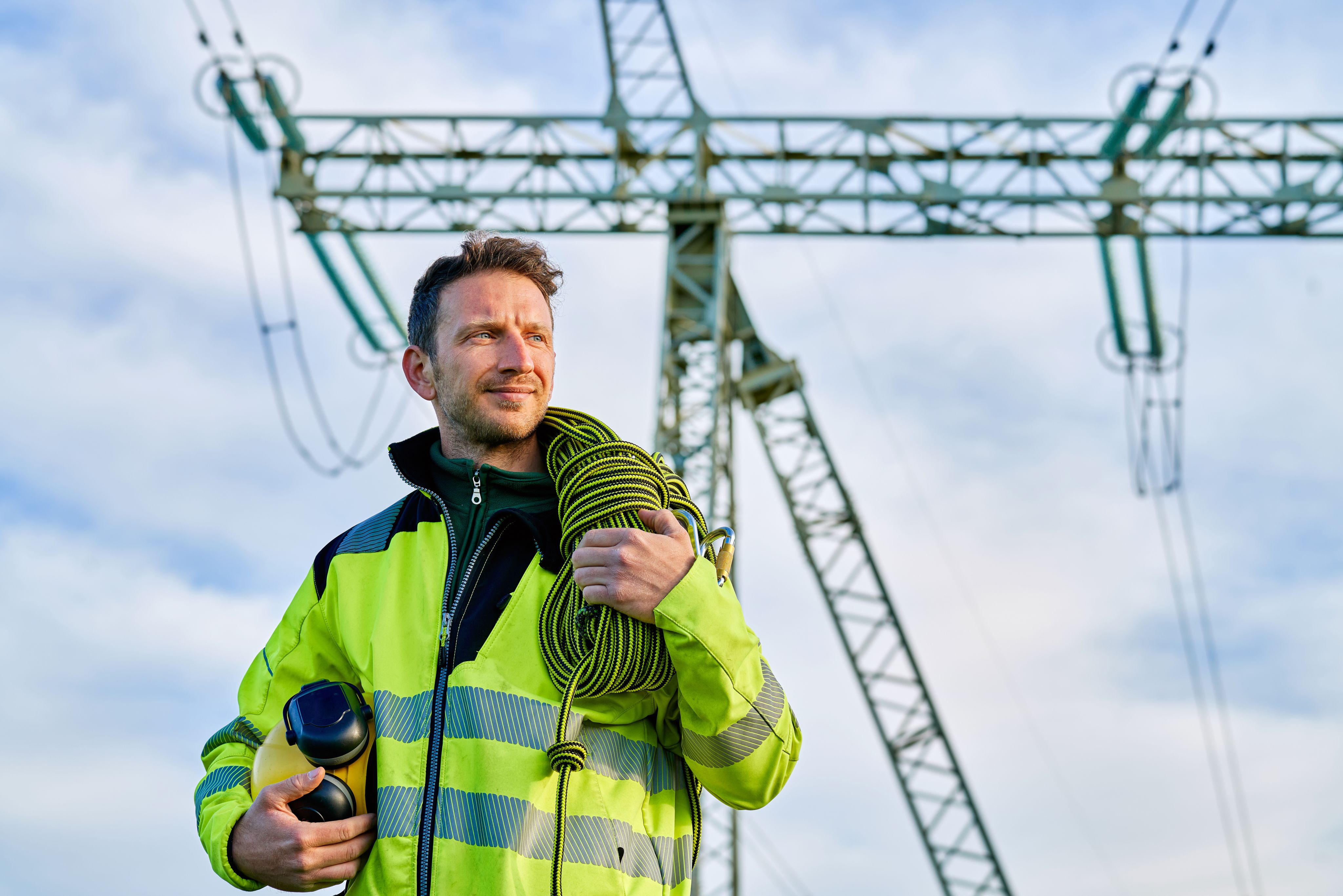 Portrait of an electrical engineer standing in front of high voltage power transformer substation.
