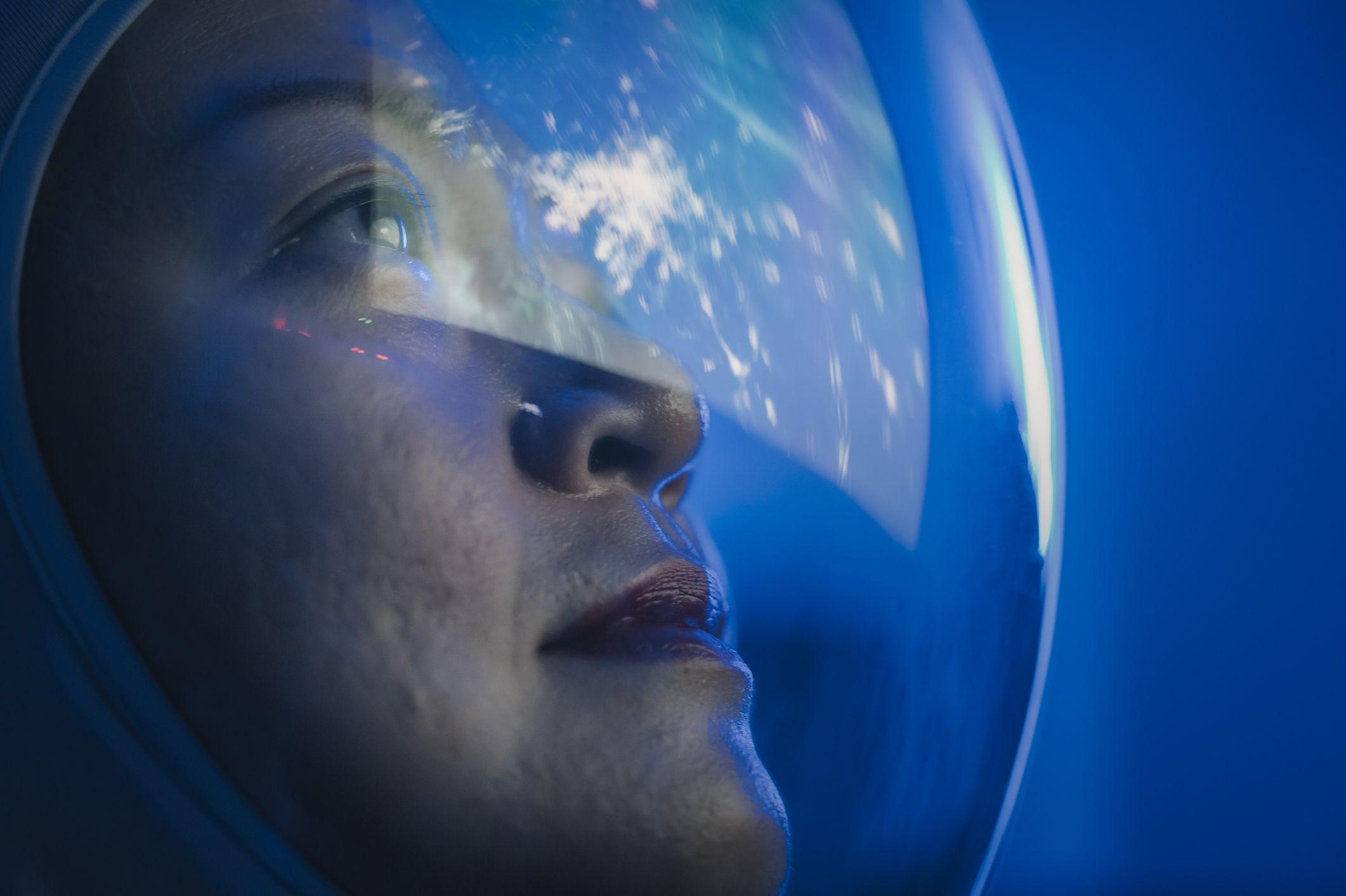 female astronaut looking at earth reflected through her visor