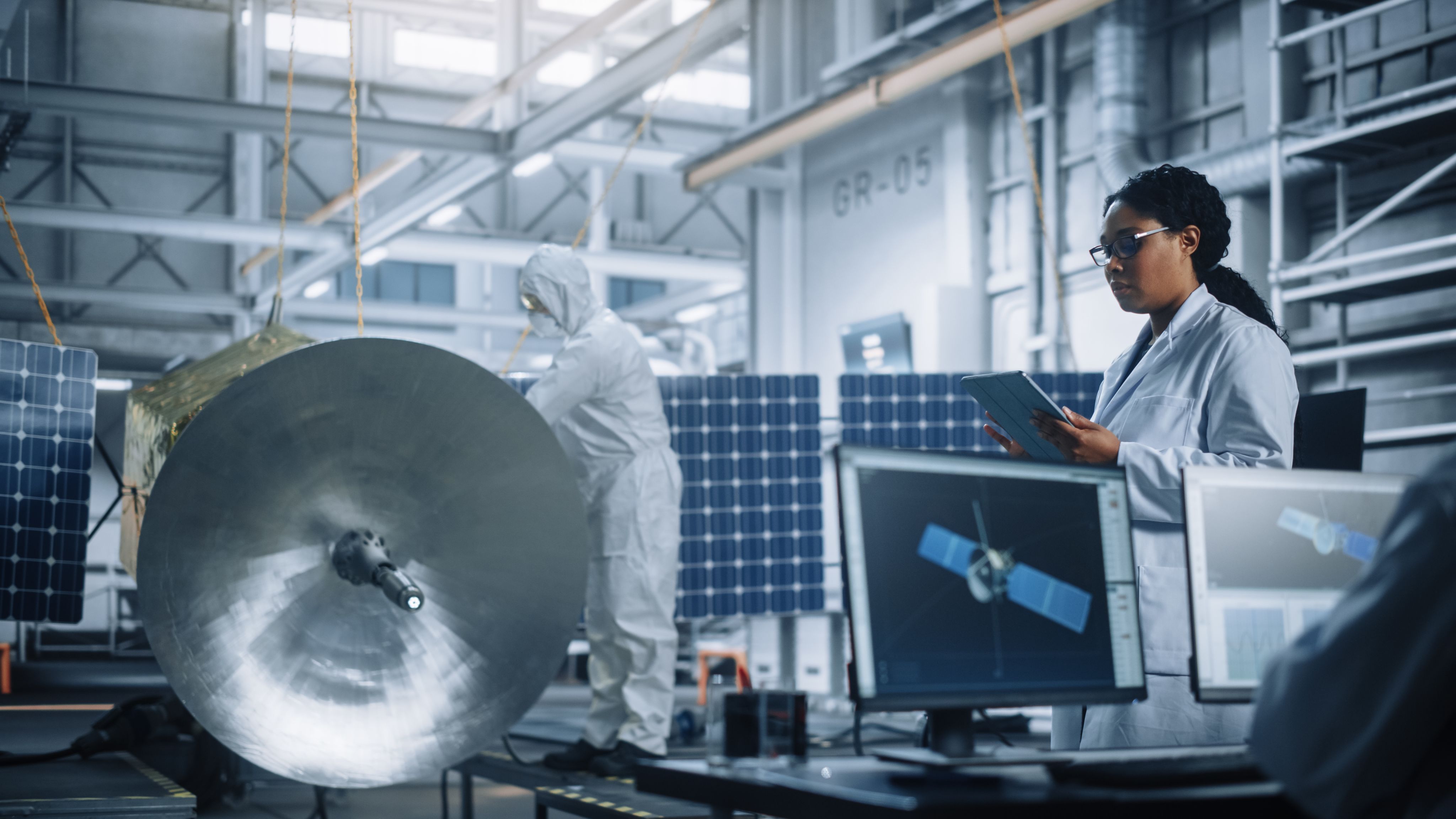 female enginerr using tablet computer whilst working on satellite construction