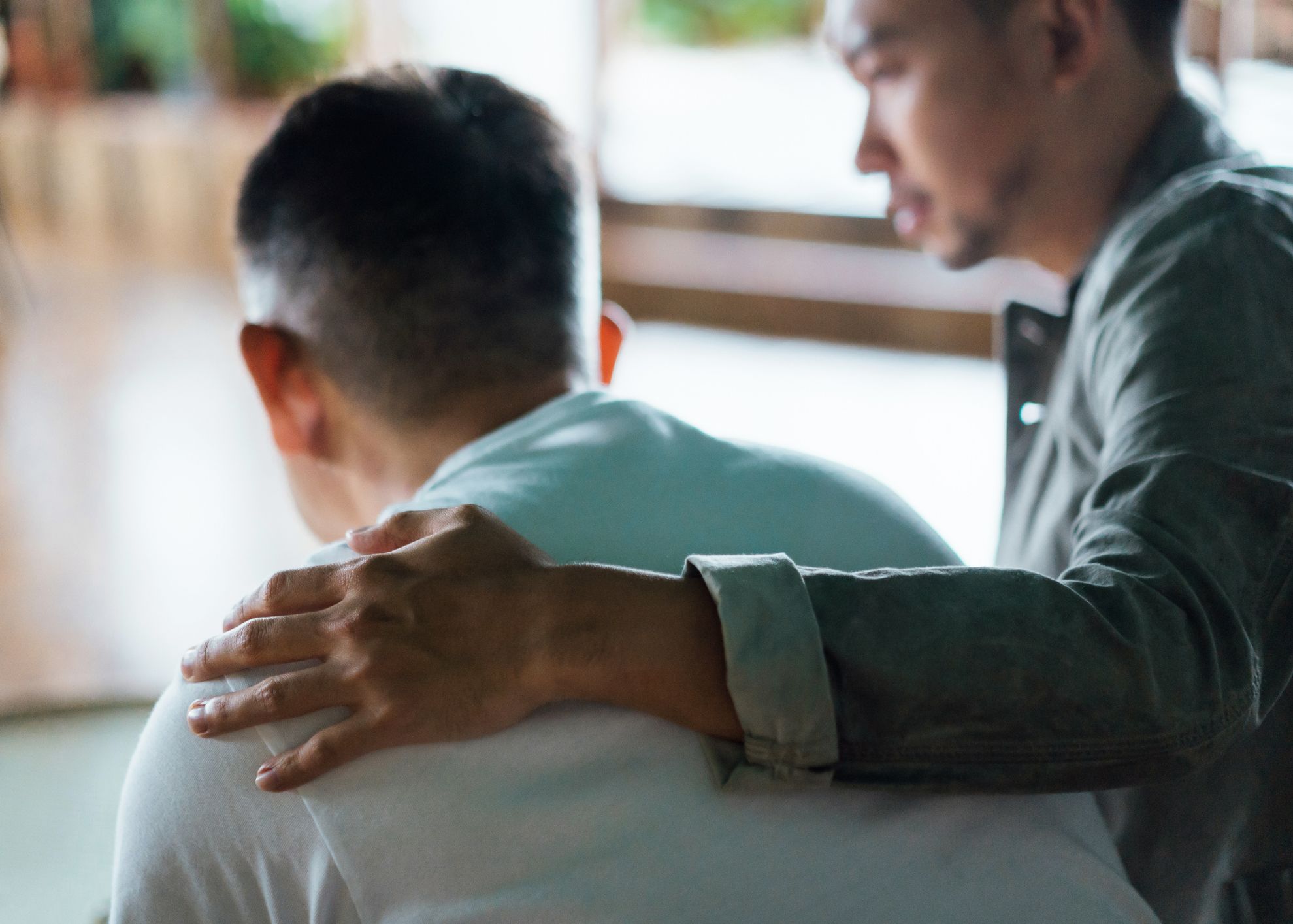 One man places his hand reassuringly on the shoulder of an older man