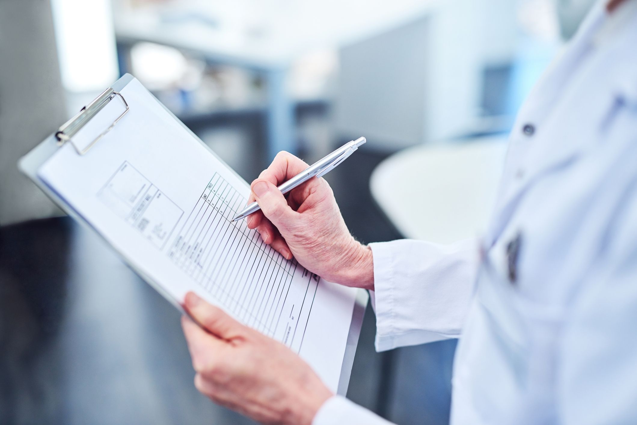 A researcher in a white coat taking notes on a clipboard