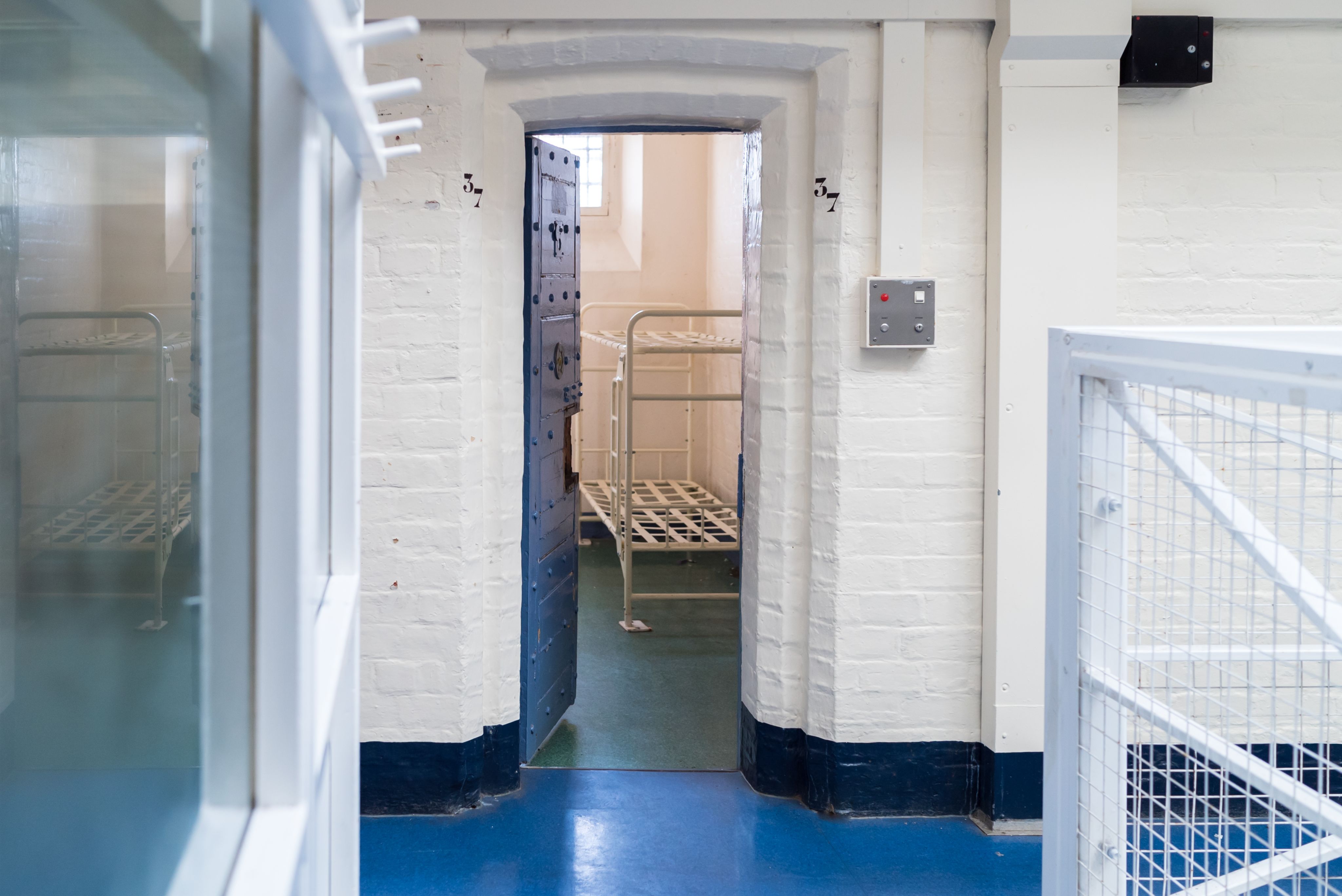 An open cell door in a prison, showing bunk beds inside
