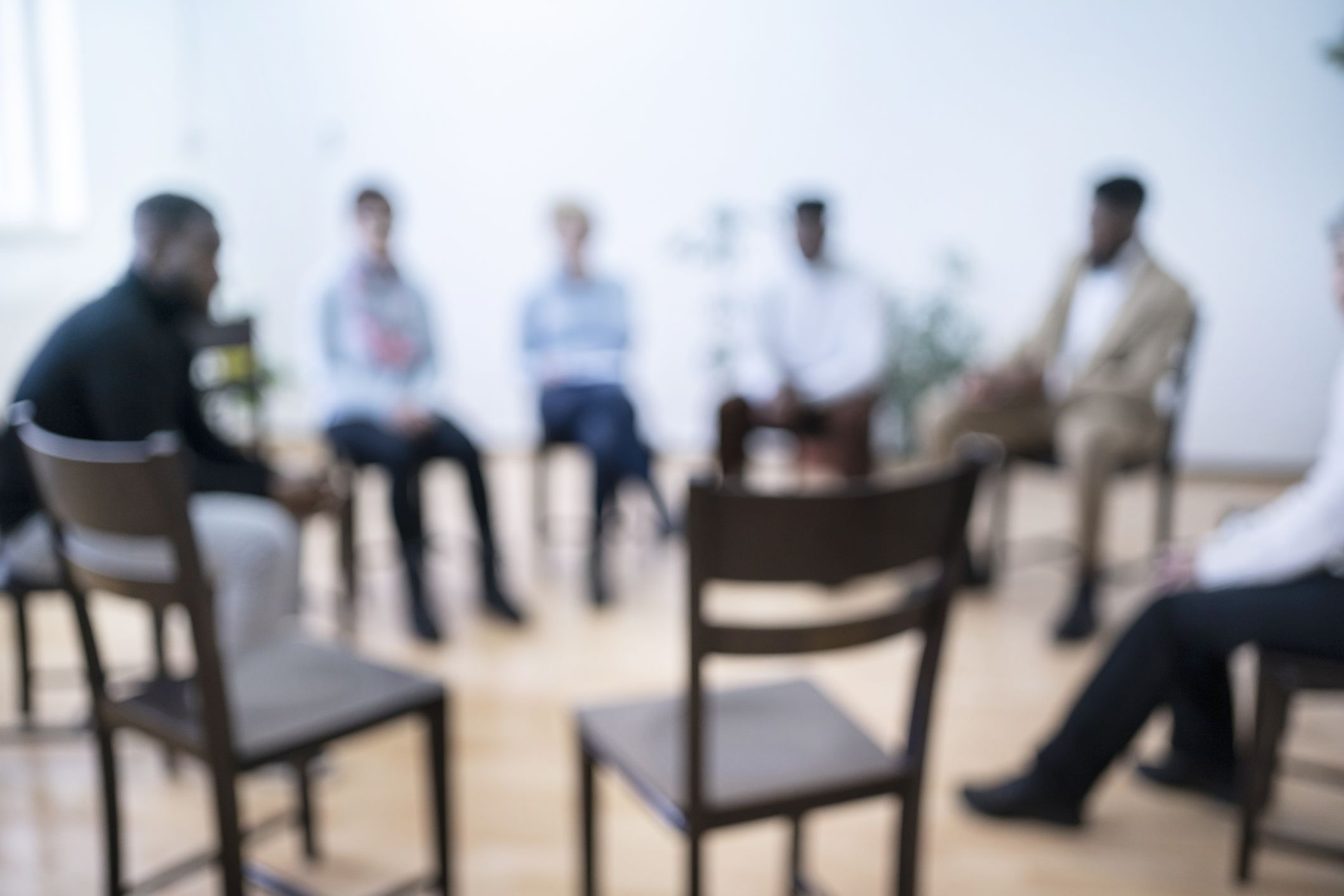 A group of people, of mixed genders and ethnicities, sit in a circle