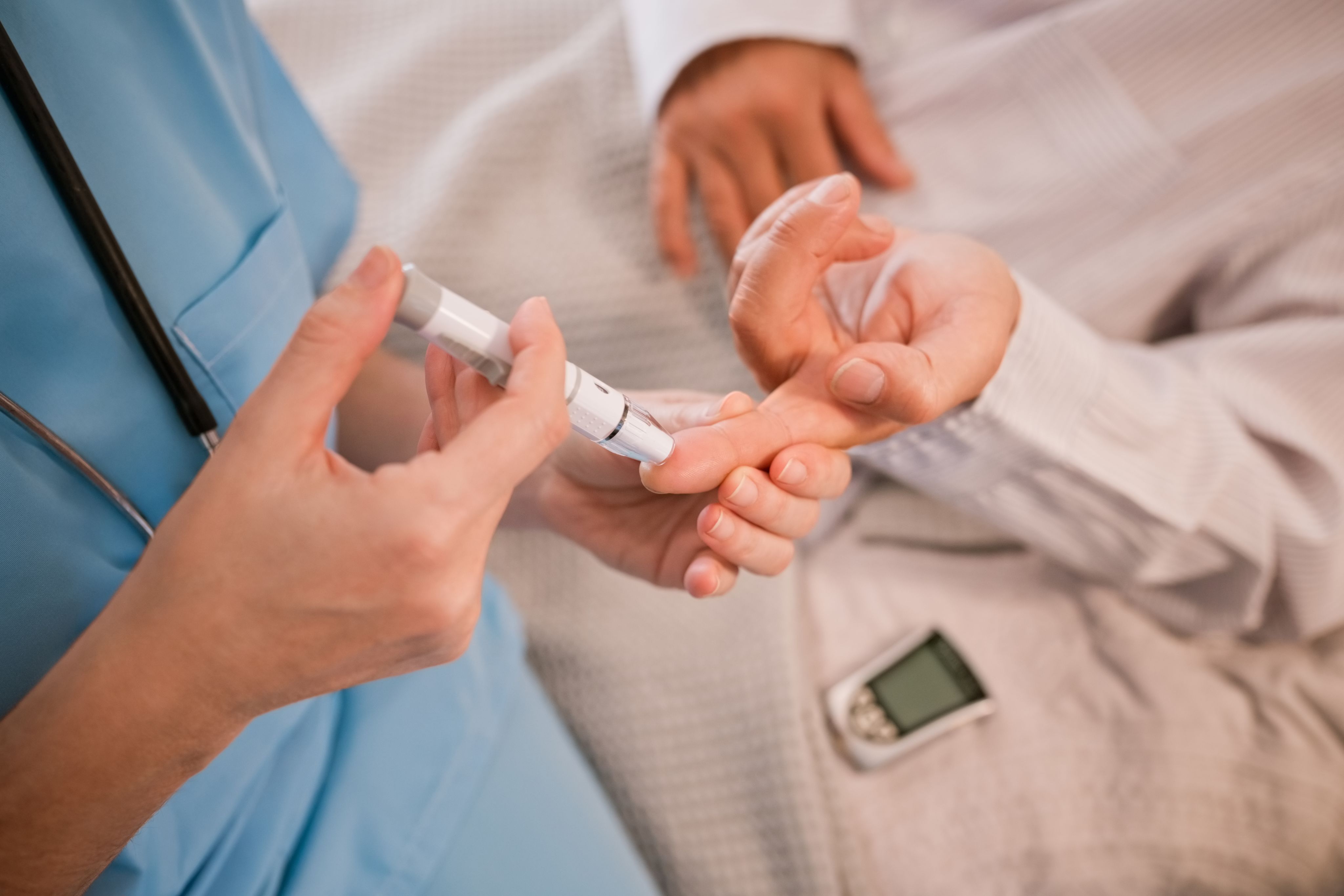 A medical worker taking a blood sample from a patient's finger to test for blood sugar levels.