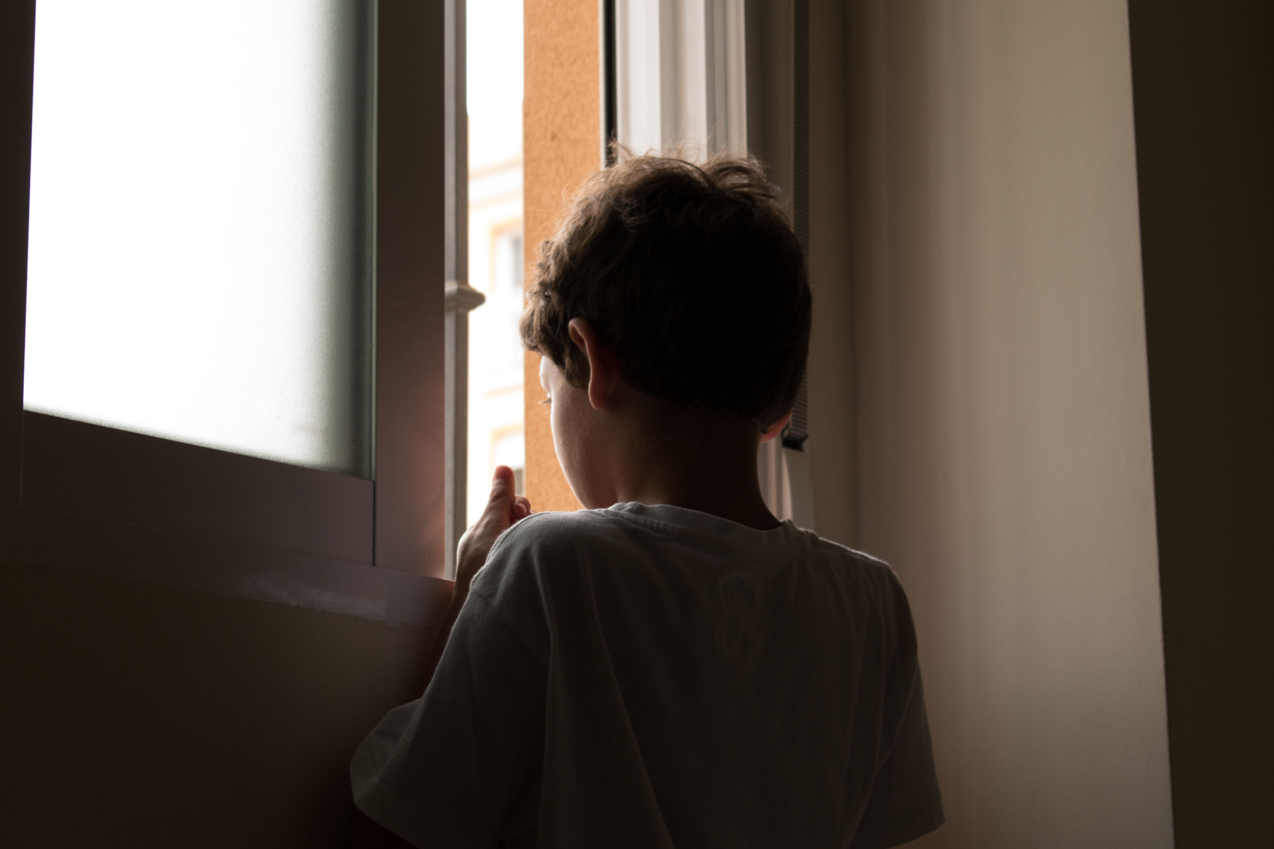 Young boy looking out of a window. 