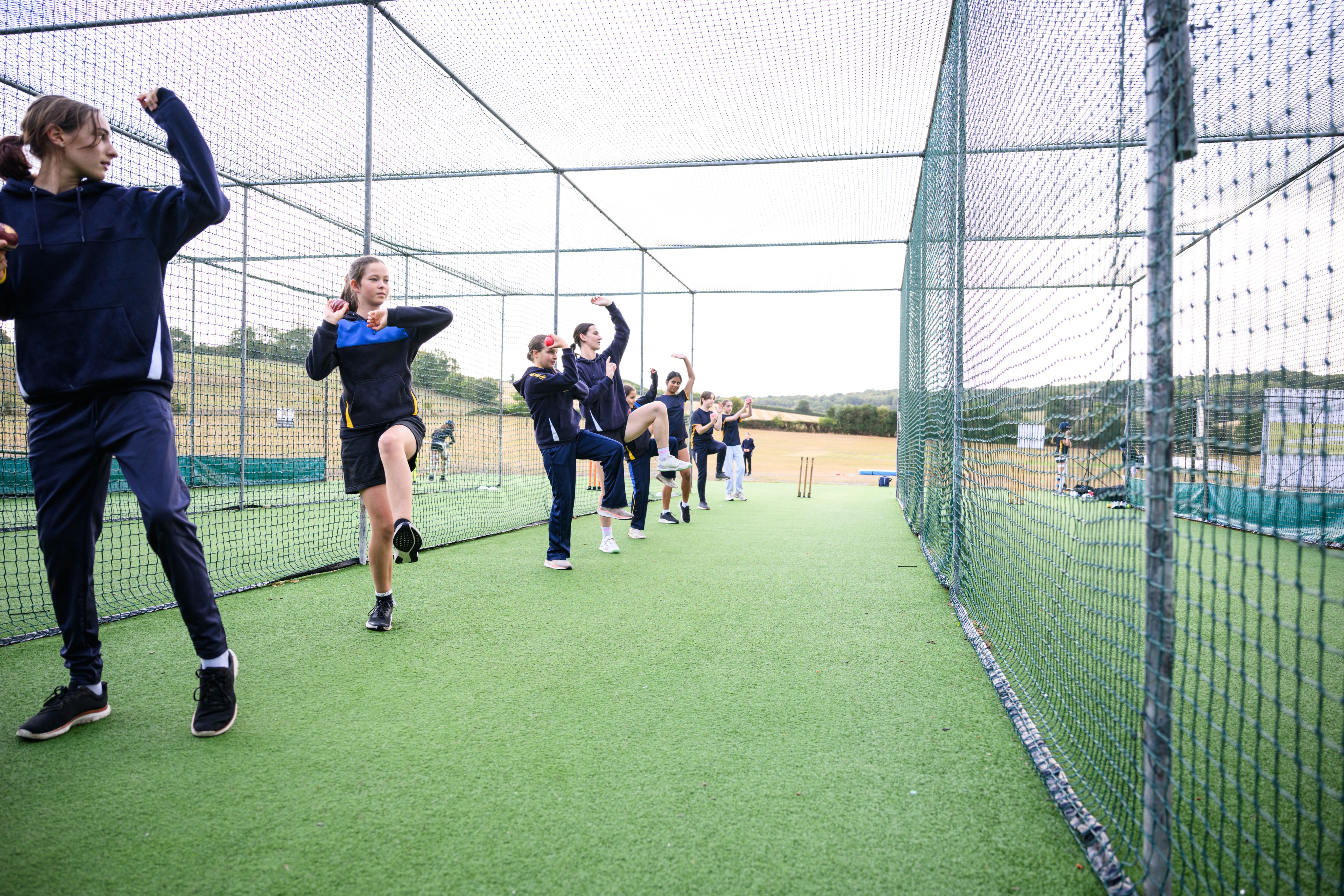 Secondary school girls lining up for bowling practice at school.